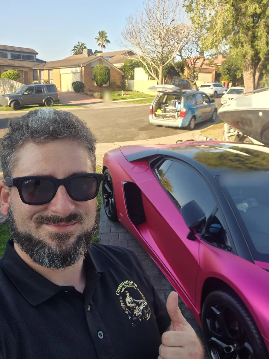 Christopher Perrotta, owner of CommandaPro Auto Detailing, in his CommandaPro polo beside a matte pink Lamborghini Aventador on a mobile job, with his detailing van open behind him.